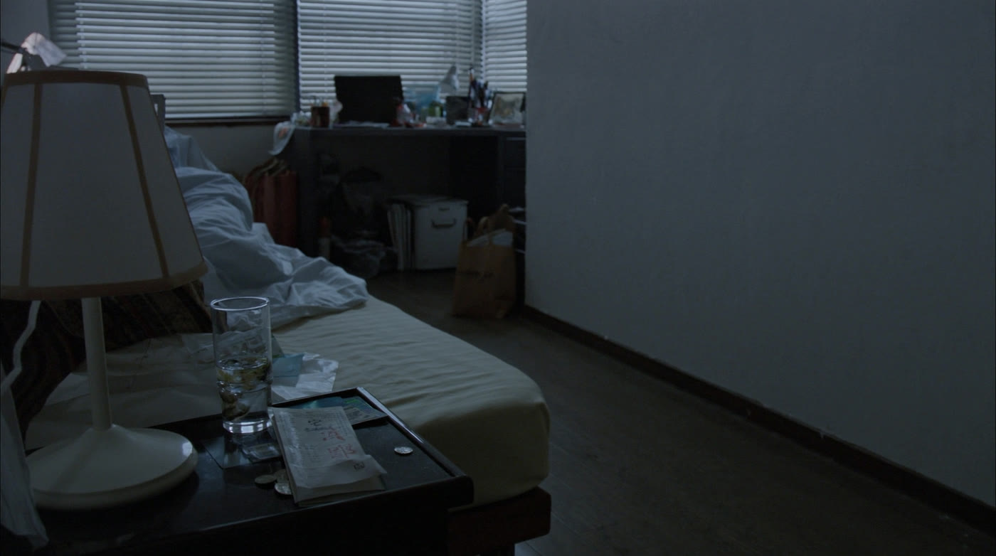The apartment set. Futon on the floor, warm lamp, blinds, a photo on the side table.